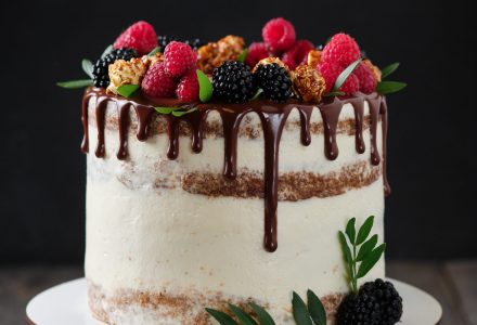Delicious and beautiful handmade cake. Confectionery for the holiday. Dessert decorated with fresh berries, green leaves and sweets.
