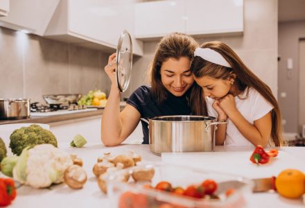 Mother with little daughter cooking together at kitchen