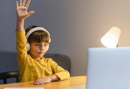 school-boy-yellow-shirt-taking-virtual-classes-raising-hand