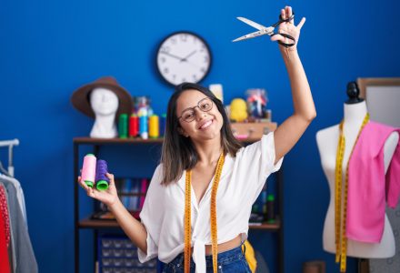 young-hispanic-woman-tailor-smiling-confident-holding-scissors-thread-sewing-studio